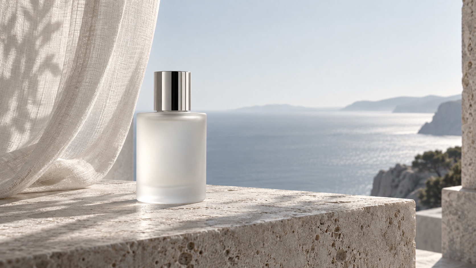 An unbranded frosted-glass fragrance bottle on limestone beside a bright coastal horizon.