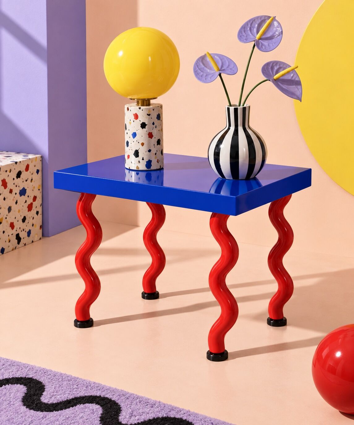A striped side table, graphic lamp and playful ceramic vase create a Memphis furniture vignette.