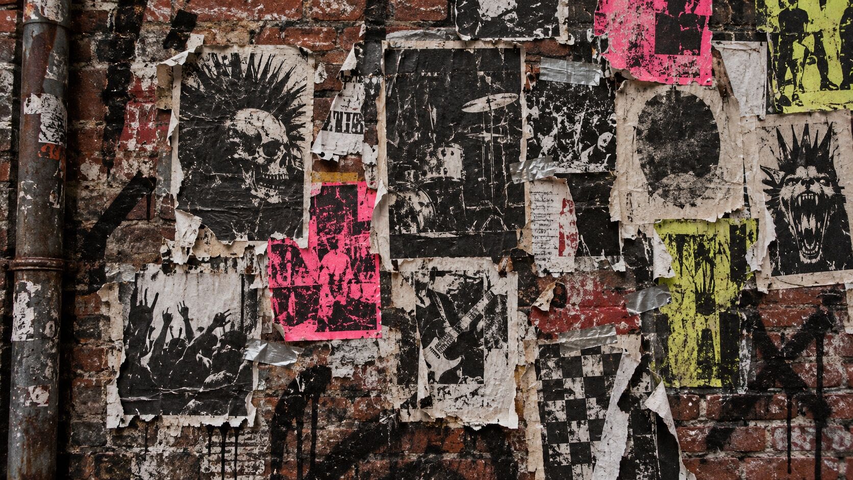A ripped punk poster wall layered with xerox graphics, spray marks, staples and tape.